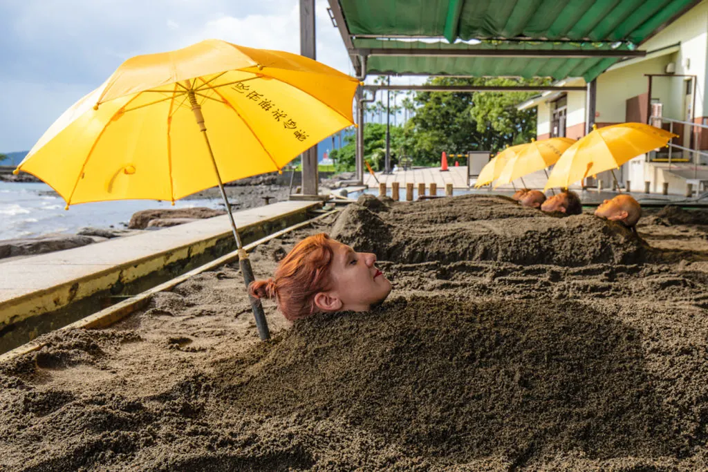 Visitors buried up to their necks in hot sand at the Beppu Beach Sandbox.