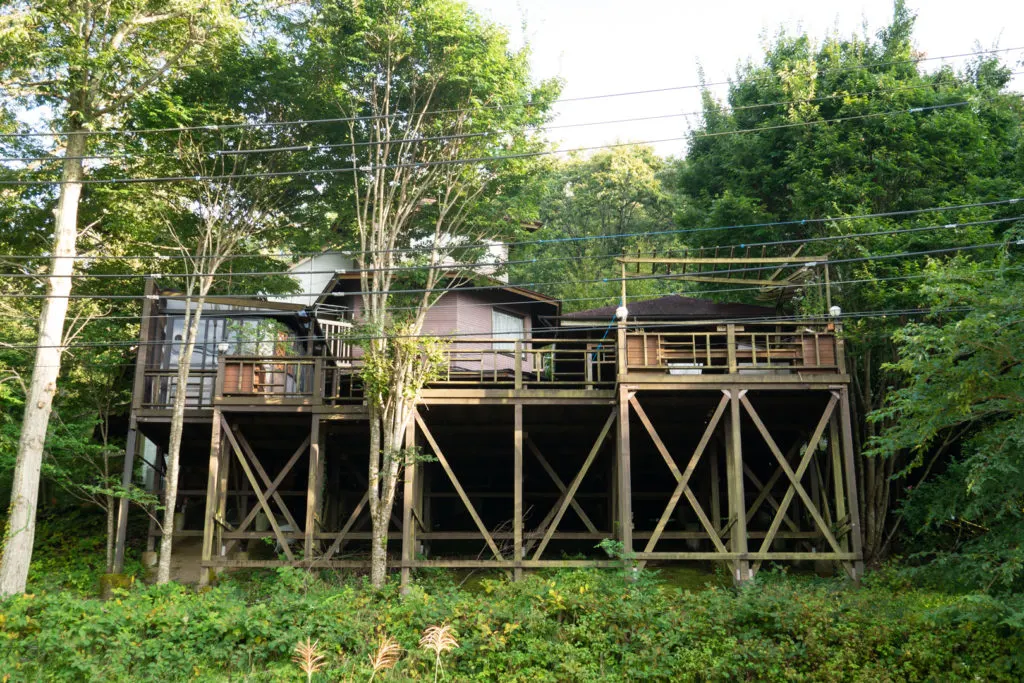 A large wooden home on stilts surrounded by trees and greenery at an Airbnb in Japan.