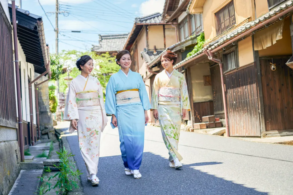 Three Japanese women walking down Chirimen Kaido wearing kimono.