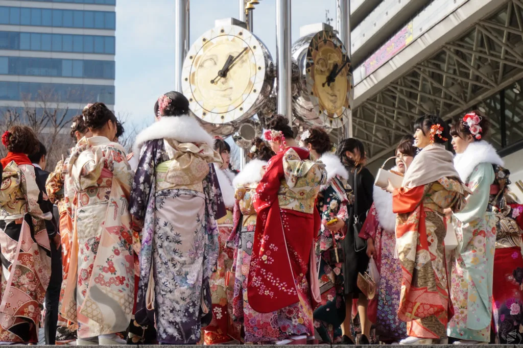 A group of Japanese women in formal furisode kimono stand underneath the clocks of Sun Plaza in Nakano Ward, Tokyo, ahead of their Coming of Age ceremony.