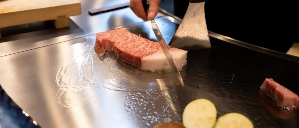 A kobe beef steak has been placed on a hot plate smeared in oil.