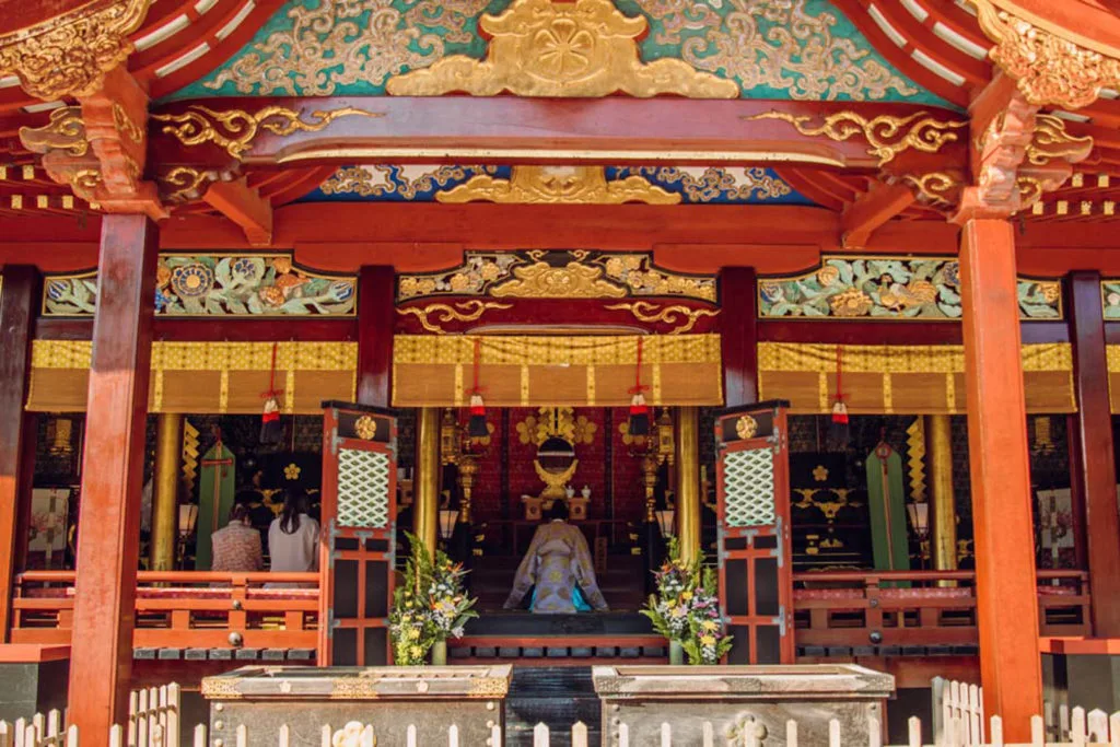 Shinto priest kneeling in prayer in the colourful inner shrine of Dazaifu Tenmangu. 