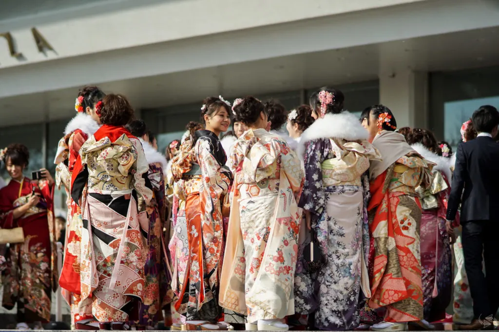 A group of Japanese women in formal furisode kimono stand chatting outside the venue of their Coming of Age Day ceremony in Tokyo.