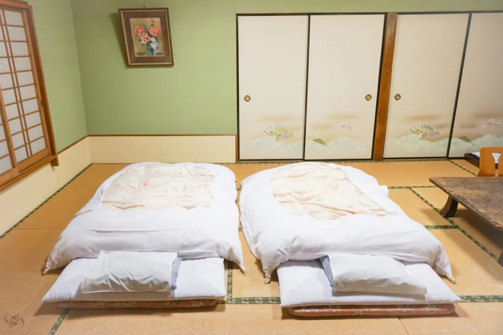 Two Japanese futons with white linen on traditional tatami mat flooring at an Airbnb in Japan.