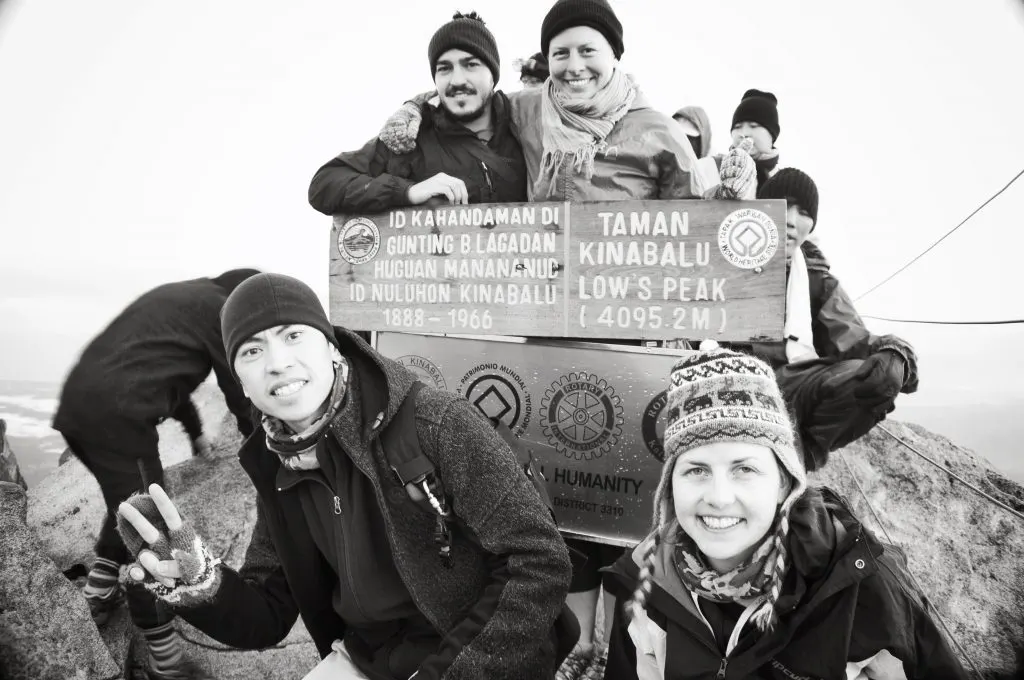 The author and her husband pose with two other climbers they met in Sabah with the sign marking the highest point on the summit of Mount Kinabalu.