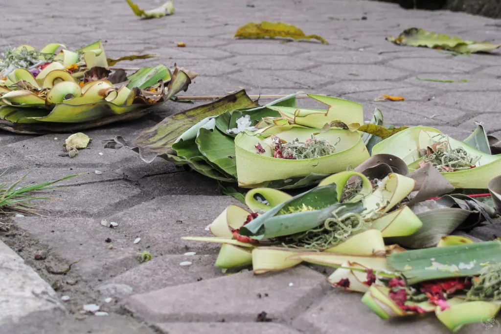 A line of balinese offerings to the gods on the sidewalk.