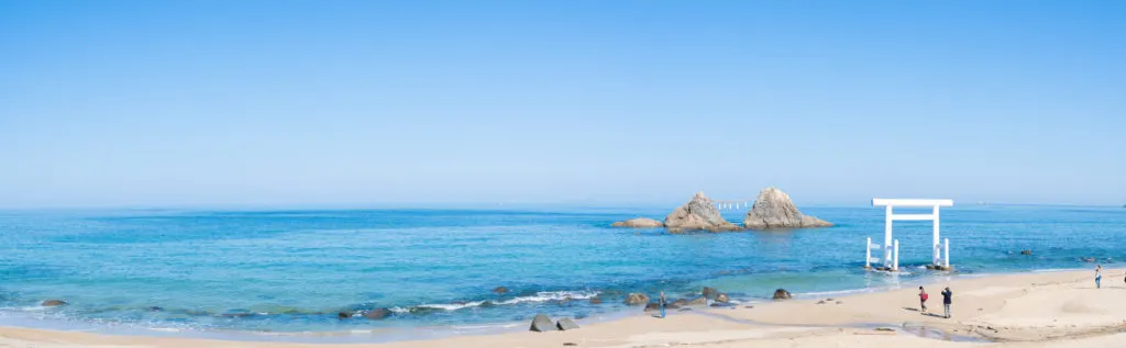 Panoramic view of Futamigaura Beach with the 'husband and wife rocks' and white torii gate in the water. 