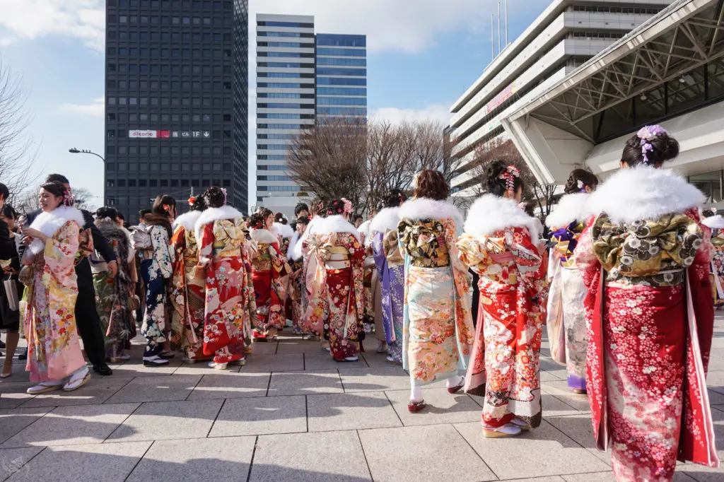 A group of Japanese women dressed in vibrantly colored furisode kimono gather in front of the venue of official Coming of Age celebrations in Nakano, Tokyo.